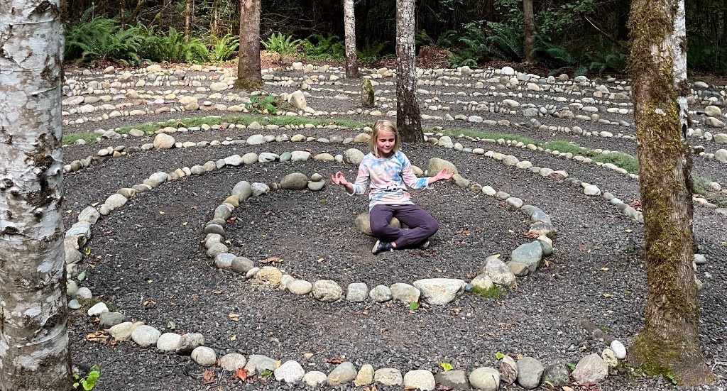 A girl sitting in the stone labyrinth in the woods at Blue Mountain Retreat