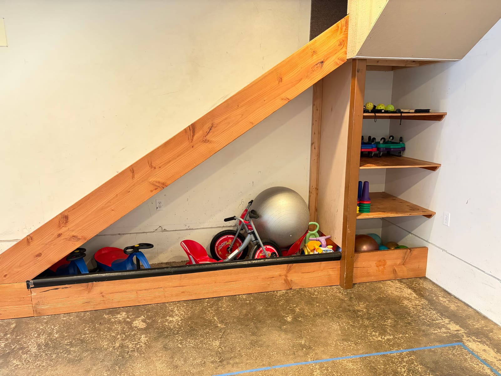 Trikes and toys under the stairs